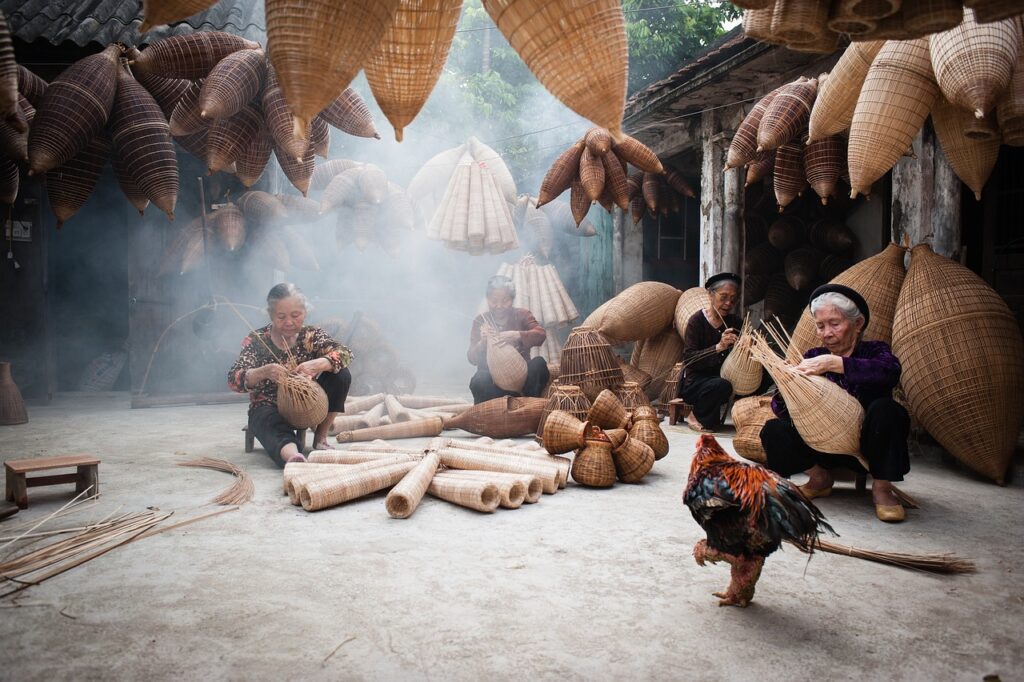 "Elderly women weave traditional bamboo baskets by hand in a smoke-filled courtyard, surrounded by hanging and stacked handmade products—showcasing sustainable craftsmanship, cultural heritage, and the eco-friendly use of natural materials."