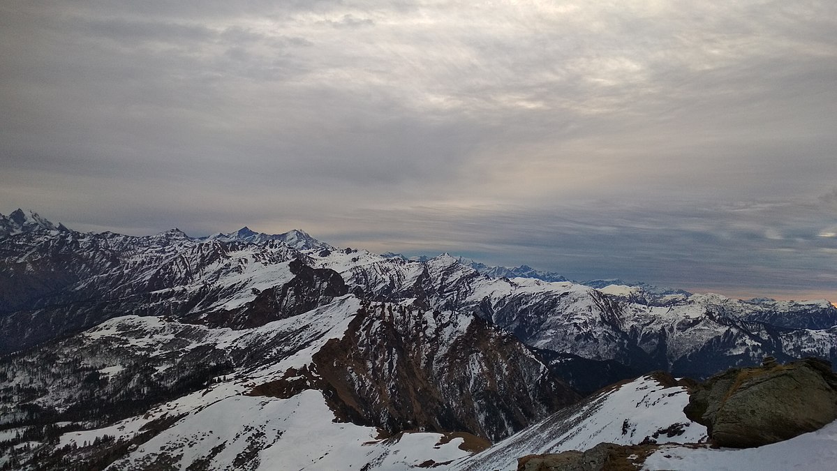 Alt Text:
A panoramic view of the majestic Himalayan ranges from Kedarkantha Summit under moody skies, ideal for eco-conscious trekking in the Indian Himalayas.